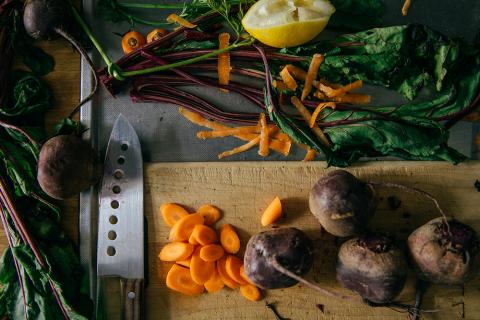 Bild på skärbräda med kniv och grönsaker intill