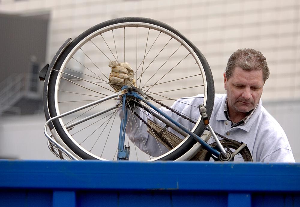 Bild på man som slänger cykel i container